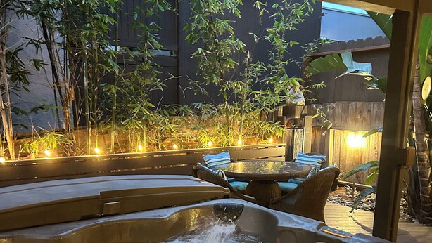 A hot tub area with a wooden deck, seating, and a bamboo backdrop. - SoCal’s Tropical Paradise with Hot Tub (Encinitas)