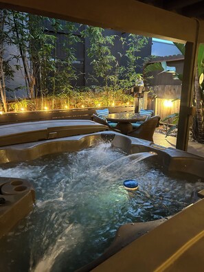 A hot tub area with a wooden deck, seating, and a bamboo backdrop. - SoCal’s Tropical Paradise with Hot Tub (Encinitas)