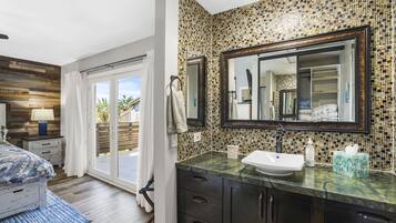 Une salle de bain moderne avec un grand miroir, un lavabo et un espace douche.