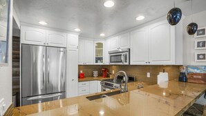 A modern kitchen with white cabinets, stainless steel appliances, and a marble countertop. - SoCal’s Tropical Paradise with Hot Tub (Encinitas)