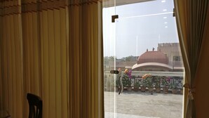 A room with a view of a building with a dome, potted plants, and a chair. - Fully Furnished 1BHK Deluxe Suite SA2 - Room, Lobby, Kitchen, bathroom, Terrace (Lucknow)