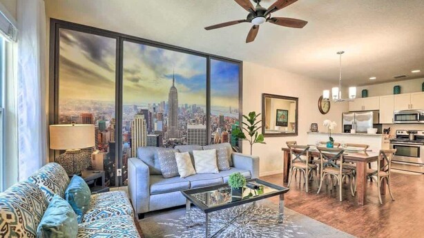 A living room with a sofa, coffee table, and a large window with a cityscape view.