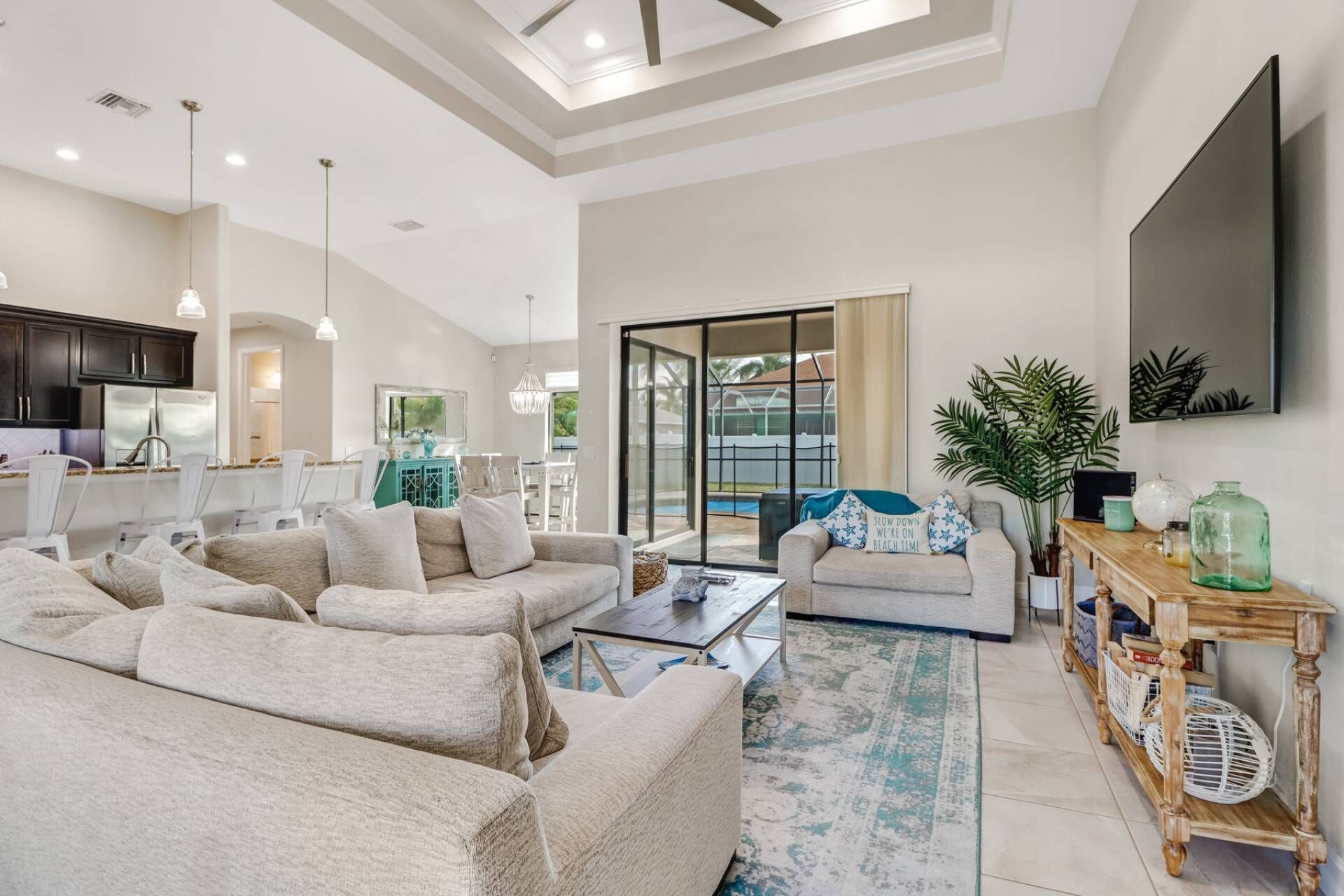 A spacious living room with a large sofa set, a coffee table, and a TV mounted on the wall.