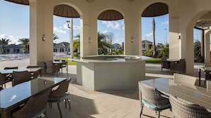 An outdoor patio area with tables and chairs, a central island, and arched ceilings. - Championsgate Charm! 9 BR, Theming & Game Room (Davenport)