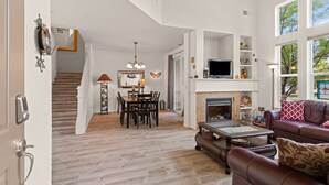 A spacious living room with a fireplace, a dining area, and a staircase leading to an upper level. - Old Mill Proxi - Hot Tub, Steps to Old Mill, Close to Downtown, Fireplace, AC, Pet Friendly (Bend)