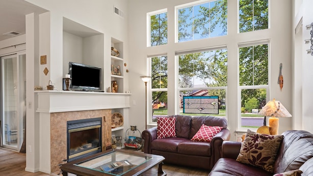 A living room with a fireplace, leather sofa, and large windows offering a view of the outdoors. - Old Mill Proxi - Hot Tub, Steps to Old Mill, Close to Downtown, Fireplace, AC, Pet Friendly (Bend)