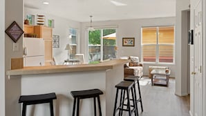 A kitchen with a bar area, bar stools, a refrigerator, and a window with blinds. - Old Mill Proxi - Hot Tub, Steps to Old Mill, Close to Downtown, Fireplace, AC, Pet Friendly (Bend)
