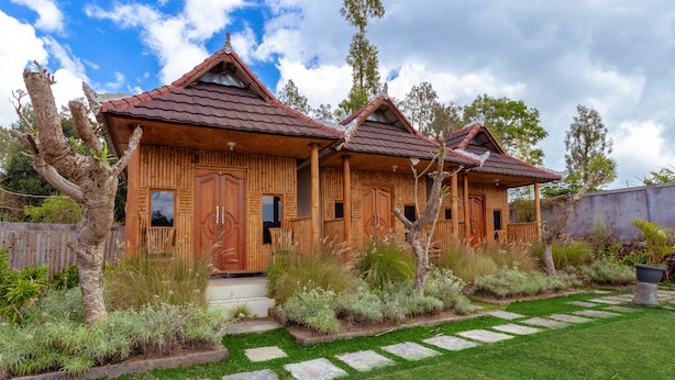 Una casa de madera con tejado de baldosas, rodeada de un jardín cuidado y un sendero de piedra.