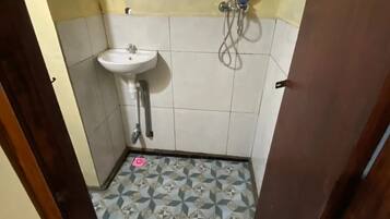 A small bathroom with a white sink, a shower, and a patterned floor.