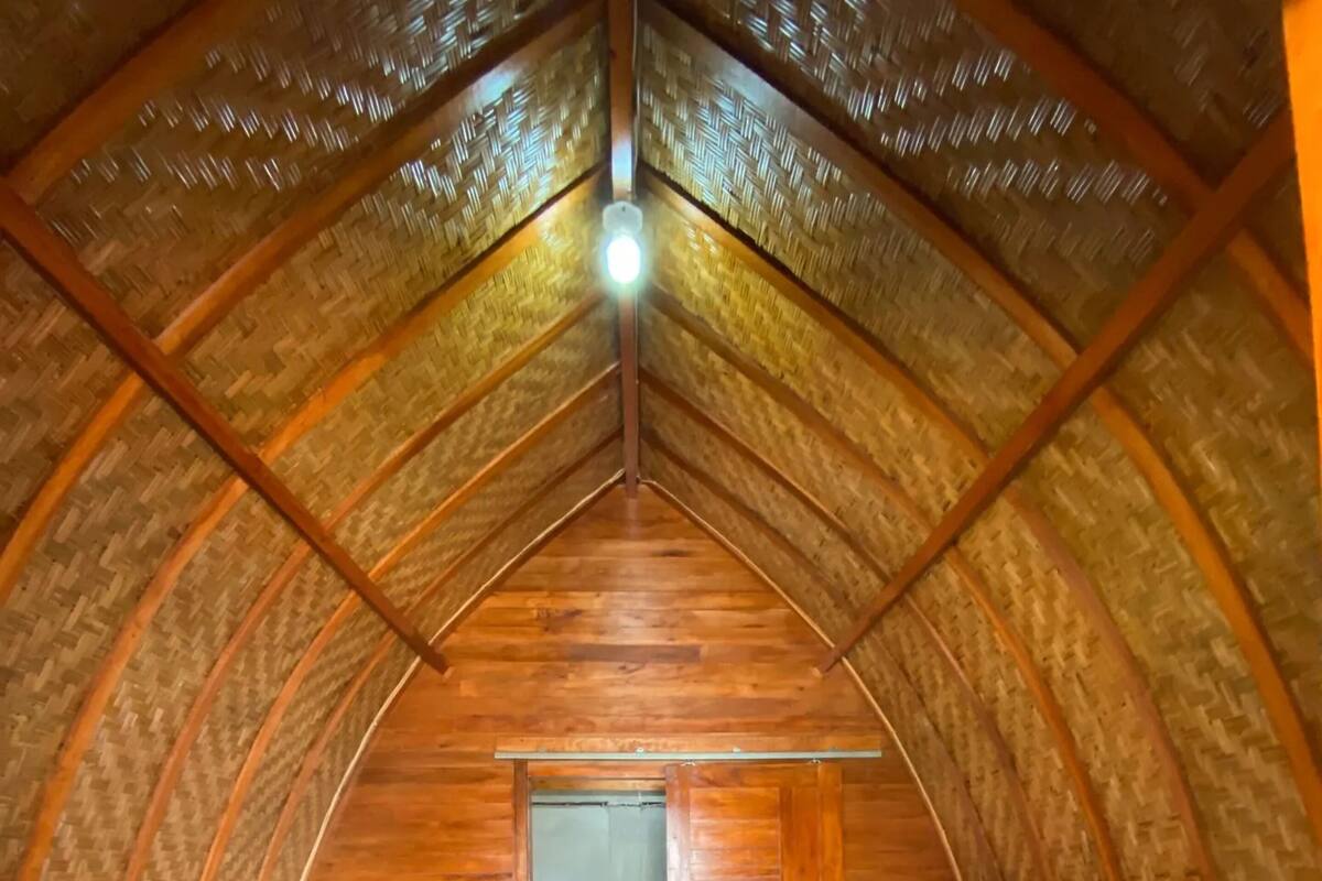 Ein gemütlicher Raum mit Holzbalkendecke, einem Bett, Kissen und einem kleinen Tisch.