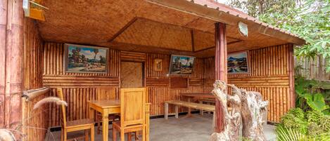 Ein rustikales Holzhaus mit überdachter Veranda, Holzmöbeln und gerahmten Bildern an den Wänden.
