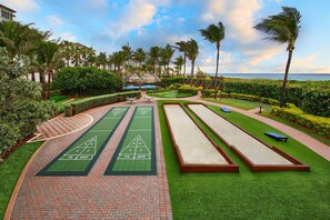 A croquet field with a brick pathway, palm trees, and a view of the ocean. - Marriott Ocean Pointe - Spacious 1BR Condo - Full Kitchen - Oceanside (Palm Beach Shores)
