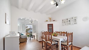 A dining area with a white table, wooden chairs, and a chandelier. - Finca El Campo: Pet-Friendly with Air Conditioning, Terrace & Garden (Arcos de la Frontera)