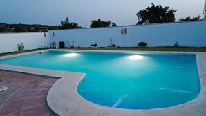 A rectangular swimming pool with a curved edge, surrounded by a paved deck. - Finca El Campo: Pet-Friendly with Air Conditioning, Terrace & Garden (Arcos de la Frontera)