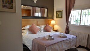 Une chambre d’hôtel avec un lit, une table de chevet, une lampe, une fenêtre avec des rideaux et un radiateur.