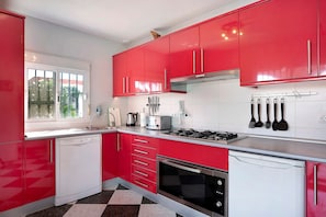 A kitchen with red cabinets, a dishwasher, a stove, and a window.