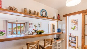 Una cocina con encimeras de madera, dos taburetes de bar, un carrito pequeño y una estantería.