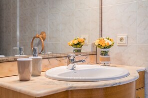 Une salle de bain avec un lavabo, un miroir et deux vases de fleurs.