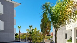 Ein Innenhof mit modernen Gebäuden, Blumentöpfen und blauem Himmel.