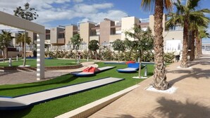 A modern resort with a pool area, palm trees, and a clear sky. - "Fantastic apartment" with Pool, Whirlpool, Wi-Fi, A/C, Balcony & Terrace (Torrevieja)