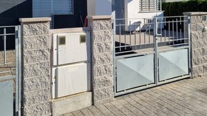 Ein modernes Gebäude mit einem verschlossenen Eingang, einer kleinen Veranda und blauem Himmel.