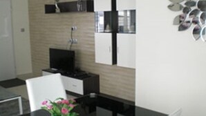Eine moderne Küche mit Fernseher, weißen Schränken und einem dekorativen Wandbild.