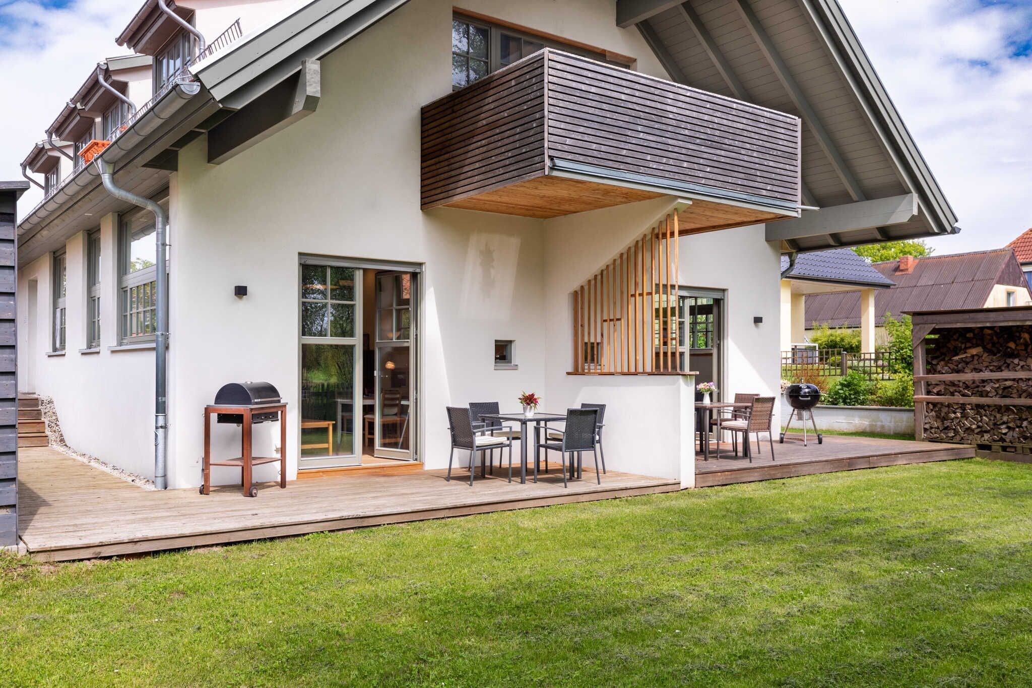 Une maison moderne dotée d’une terrasse, d’un espace salon extérieur et d’un barbecue.