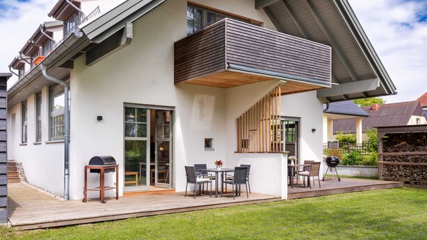 Een modern huis met terras, buitenmeubels en een barbecue.