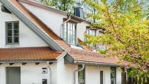 Een wit gebouw met een schuin dak, schoorsteen en een duidelijke deur.