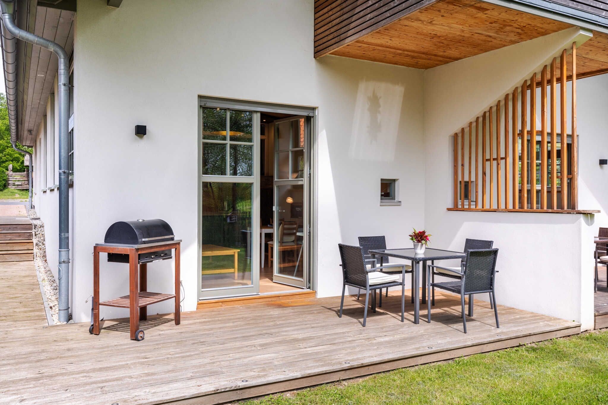 Une terrasse extérieure moderne, équipée d’un barbecue, d’une table à manger et de chaises.