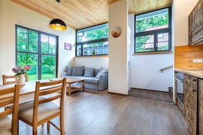 Um interior moderno com área de jantar, sofá, janelas amplas e piso de madeira.