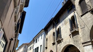 Una stretta via fiancheggiata da edifici storici, con un cartello di un ristorante e il divieto di parcheggio ben visibili.