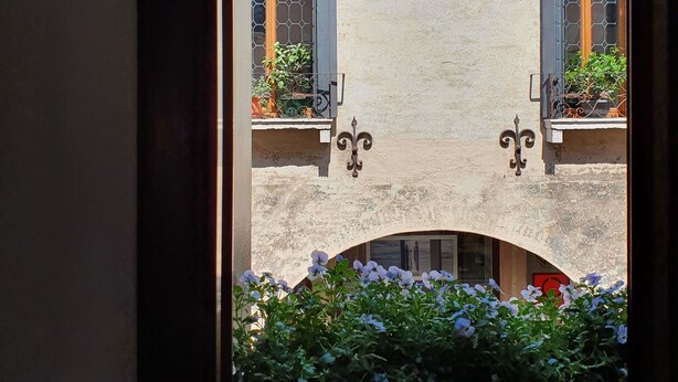 Una veduta di un edificio con due balconi, ciascuno con una finestra e una porta, e un piccolo arco al centro.