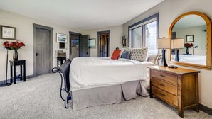 A bedroom with a bed, dresser, mirror, and a door leading to another room. - Platinum Frost Fire, Hot Tub access, Near Slopes! (Keystone)