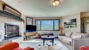 A living room with a fireplace, a television, a sofa, and a coffee table. - Platinum Frost Fire, Hot Tub access, Near Slopes! (Keystone)