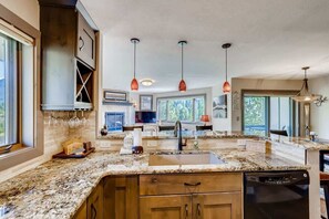 A modern kitchen with granite countertops, wooden cabinets, and pendant lighting.