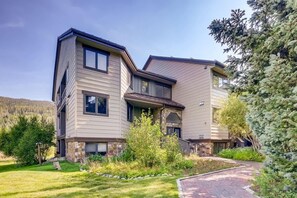 A modern two-story house with a stone foundation, large windows, and a well-maintained garden.