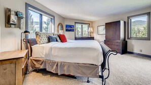 A bedroom with a large bed, a dresser, a desk, and two windows offering a view of the outdoors. - Platinum Frost Fire, Hot Tub access, Near Slopes! (Keystone)