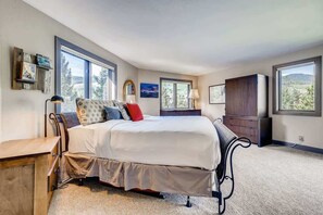 A bedroom with a large bed, a dresser, a desk, and two windows offering a view of the outdoors. - Platinum Frost Fire, Hot Tub access, Near Slopes! (Keystone)