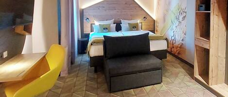 Un dormitorio con cama, sofá, una silla y estante de madera.