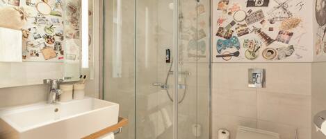 A modern bathroom with a glass-enclosed shower, a white sink, and a toilet.