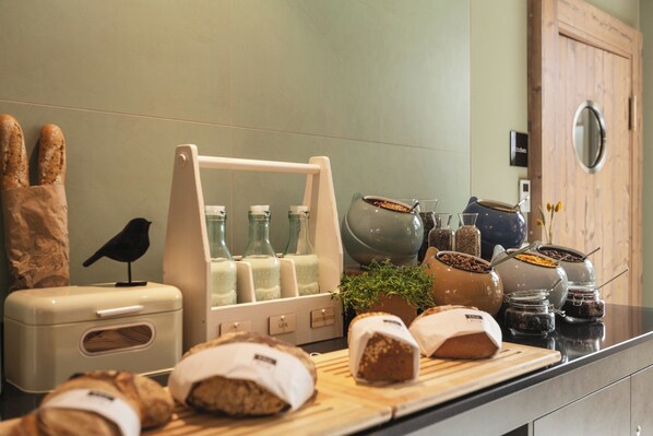 A kitchen counter with bread, jars, and a bird figurine. - Holiday Inn – the niu, Mill Cologne Mülheim by IHG (Cologne)