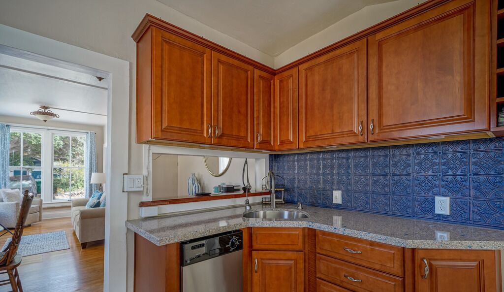 Una cocina con armarios de madera, salpicadero de azulejos azules y lavavajillas.