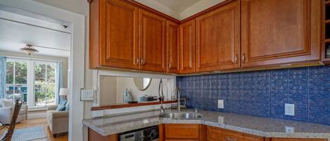 Una cocina con armarios de madera, salpicadero de azulejos azules y lavavajillas.