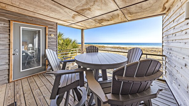 A covered outdoor seating area with a table and chairs, overlooking a beach. - Needle Rush Point A24 | Walk to FloraBama | 2 Pools | 2 Boat Docks w/Slips | My Beach Getaways (Pensacola)