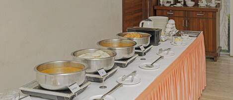 A breakfast buffet with various food items and serving utensils.