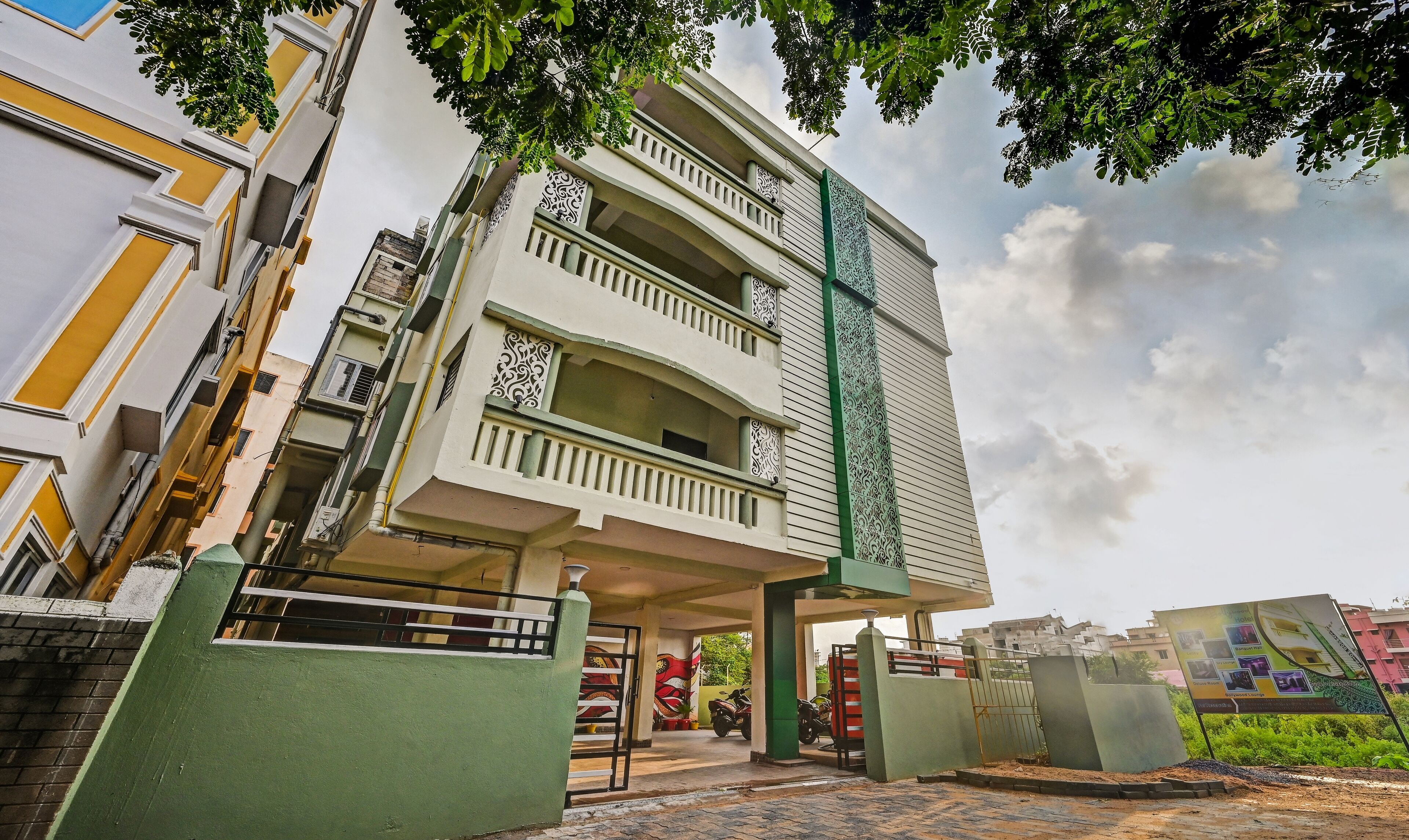 A multi-story building with balconies, a gated entrance, and a signboard.