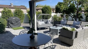 An outdoor patio area with a round table, white chairs, a grey sofa, and a covered grill. - Perfectly located in Scottsdale to ALL  (Scottsdale)