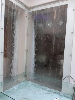 Une douche entièrementClose avec des parois en verre sur lesquelles l’eau s’écoule.