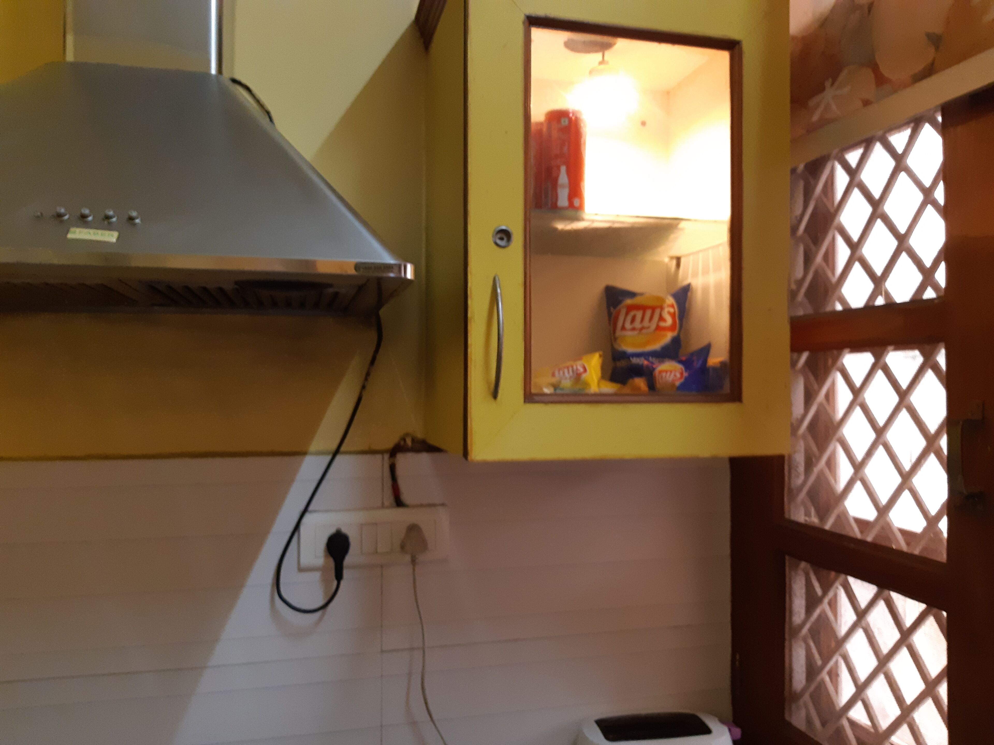 A kitchen with a yellow cabinet containing snacks, a stove, and a power outlet.